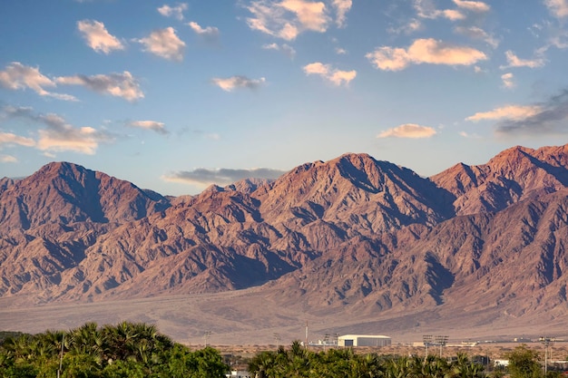 Cordillera de las montañas Eilat Camine por las montañas cerca del Golfo del Mar Rojo en Israel Cordillera y cielos despejados Fantásticamente hermoso paisaje desierto palmera nubes y cielo azul