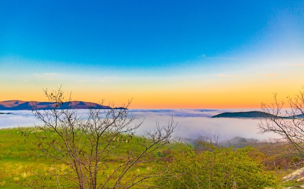 Cordillera con siluetas visibles a través de la colorida niebla matutina.