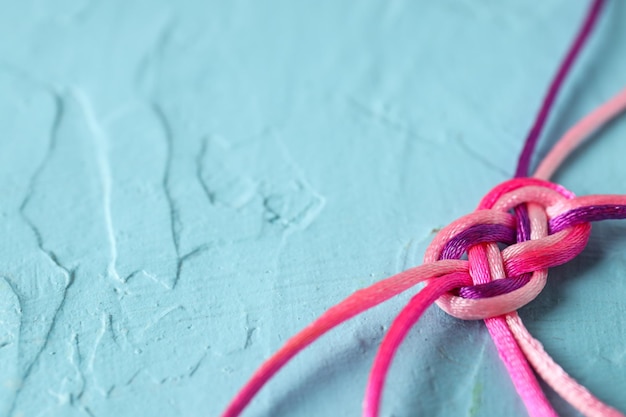 Cordões trançados amarrados na forma de um sinal de infinito em um fundo azul Conceito de comunicação Lugar para texto