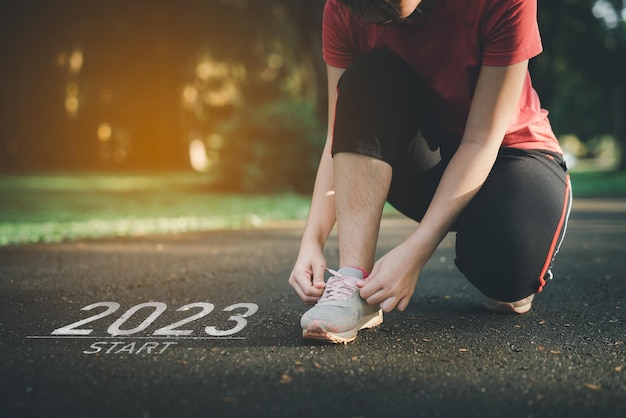 Los cordones de los zapatos de la corredora deportiva comienzan en el nuevo año 2023 La puesta en marcha de la mujer corredora que corre en la pista de carreras de la naturaleza va a Goal of Success Gente que corre como parte del número 2023 Atención médica deportiva