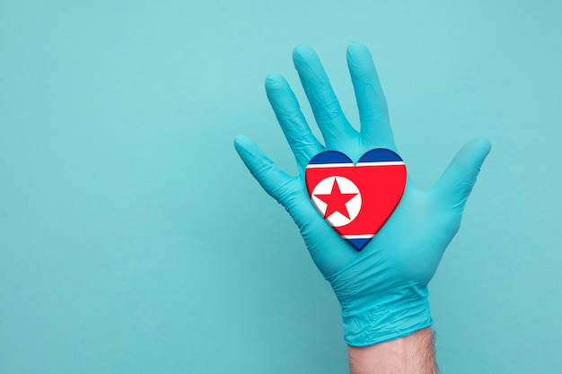 Foto corea del norte salud médica corazón enfermera mano sosteniendo la bandera del corazón del país