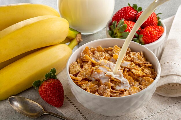 Cornflakes in der Schüssel mit Beeren und Milch auf dem Tisch