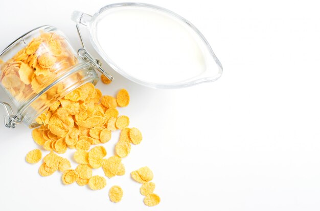 Cornflakes in einem Glasbehälter und Milch. Weißer Hintergrund. Speicherplatz kopieren