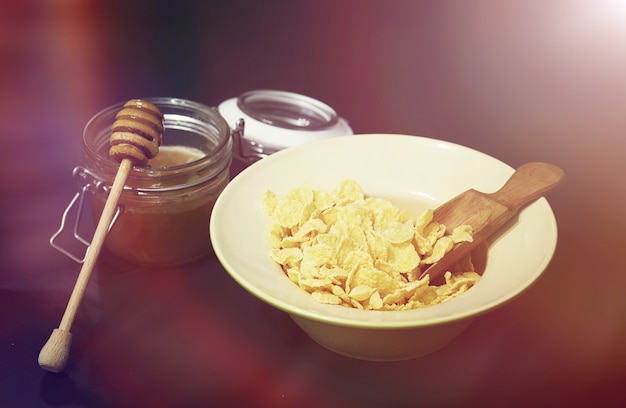 Cornflakes in einem Teller. Frühstück aus Flocken mit Honig und Milch. Schnelles Frühstück mit Cornflakes