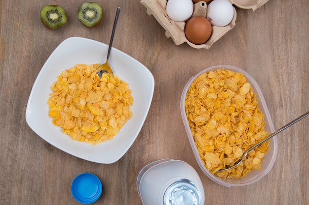 Cornflakes mit Milch und Eiern auf einem hölzernen braunen Hintergrund