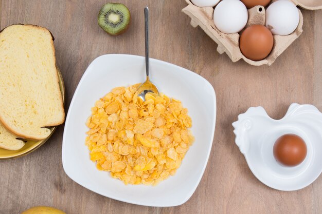 Cornflakes mit Milch und Eiern auf einem hölzernen braunen Hintergrund