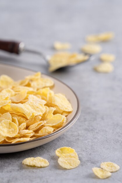 Cornflakes Schüssel Süßigkeiten mit Milch auf grauer Zementoberfläche, Nahaufnahme, frisches und gesundes Frühstück Design-Konzept.