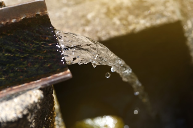 Coro de agua de manantial que fluye en una antigua fuente de pueblo rústico