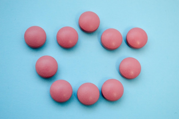 Coroa convexa volumosa rosa disposta em comprimidos em uma infecção por coronavírus de fundo azul brilhante