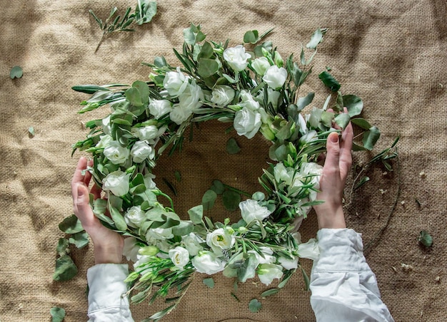 Coroa de flores com rosas brancas em fundo de juta. Decorado