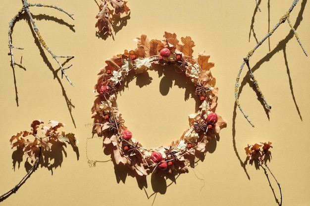 Coroa floral seca de folhas secas de outono e bagas de outono postura plana com galhos secos e folhas de carvalho em papel dourado