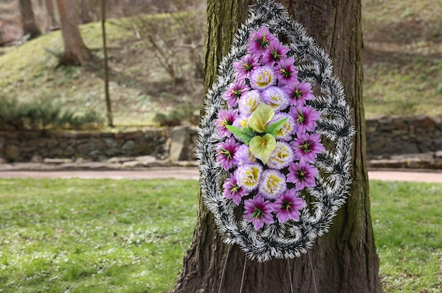 Coroa funerária de flores de plástico na árvore ao ar livre