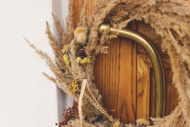 Coroa rústica de outono em close-up em latão, alça retro, porta de entrada de madeira, decoração de outono elegante da entrada da fazenda ou da varanda, arranjo de outono