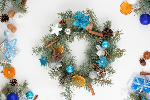 Corona de árbol de Navidad hecha en casa hecha de ramas de abeto en una pared de madera clara con bolas azules y plateadas en los colores del toro 2021.