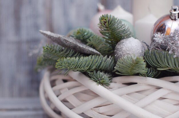 Corona de centro de mesa de invierno o Navidad con velas, juguetes de año nuevo, especias y ramas de abeto sobre fondo de madera gris