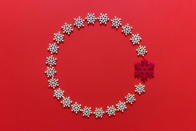 Foto corona de decoración navideña circular hecha de copos de nieve blancos sobre superficie rosa roja