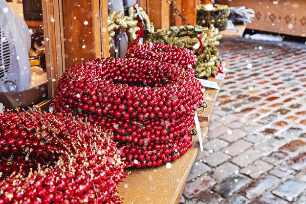 Corona decorativa artificial con frutos rojos en el mostrador durante el tradicional mercado navideño en las calles de la ciudad de Tallin