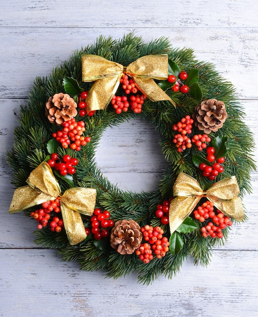 Corona decorativa de Navidad con hojas de muérdago sobre fondo de madera