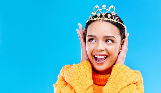 Corona de maqueta o feliz con mujer en estudio para celebración princesa y fiesta Sonrisa belleza y moda con tiara femenina sobre fondo azul y emocionada por el ganador del logro y el evento de graduación wow