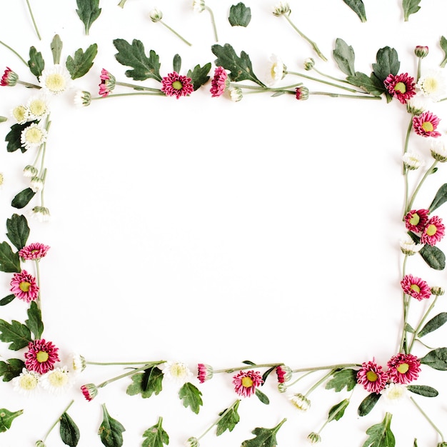 Corona de marco con flores silvestres rojas y blancas, hojas verdes, ramas en superficie blanca
