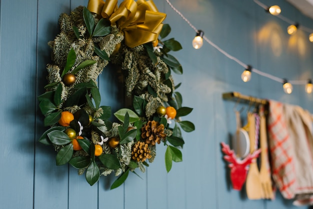 Corona de navidad colgada en la pared de molestia azul con luces, decoración de apartamento o cocina en la casa