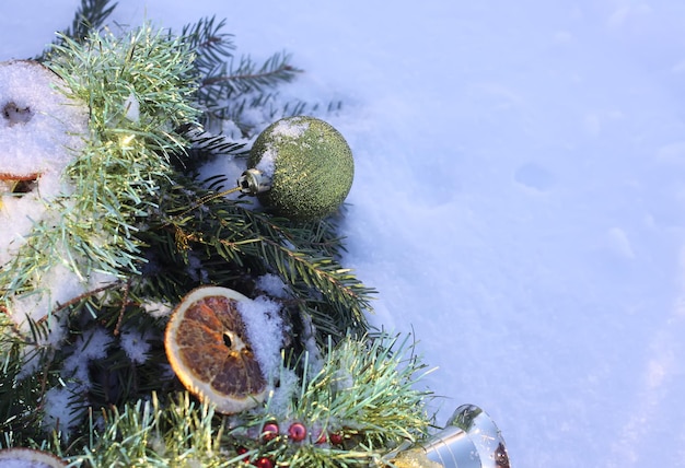 Corona de Navidad decorada con rodajas de naranja secas y bolas de colores sobre fondo blanco como la nieve.