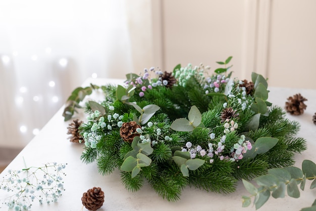 Corona de Navidad con gypsophila eucalipto y piñas en la mesa Decoración navideña hecha por uno mismo