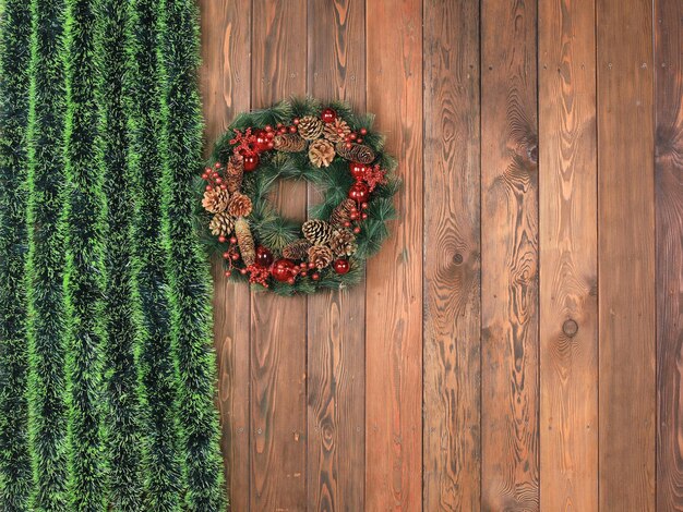 corona de navidad con oropel verde en la pared de madera