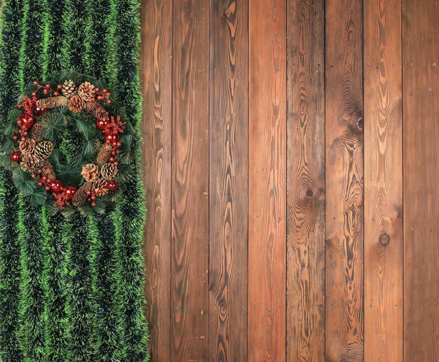 corona de navidad con oropel verde en la pared de madera