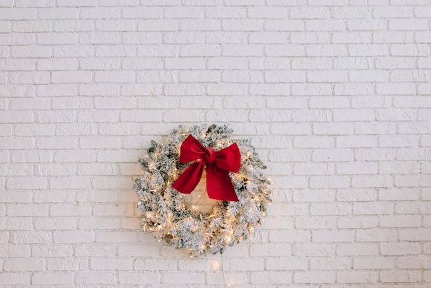 Corona de Navidad en la pared de ladrillo blanco.