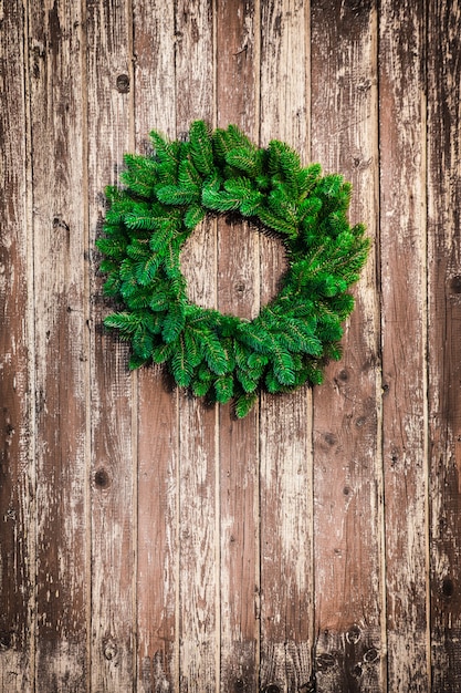 Corona de Navidad en la puerta de madera en mal estado. Fondo de vacaciones de Navidad con espacio de copia