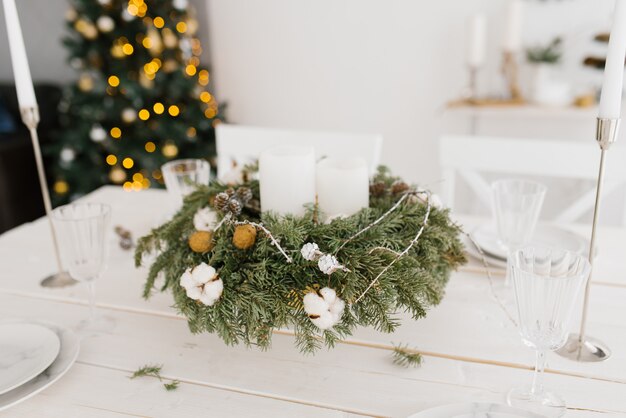 Corona de Navidad con velas blancas en la mesa festiva