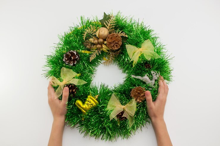 Foto corona navideña casera de oropel verde con decoración en manos de un niño