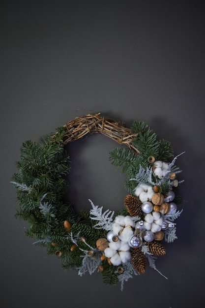 Corona navideña de enredaderas decoradas con ramas de abeto, bolas navideñas y materiales naturales,
