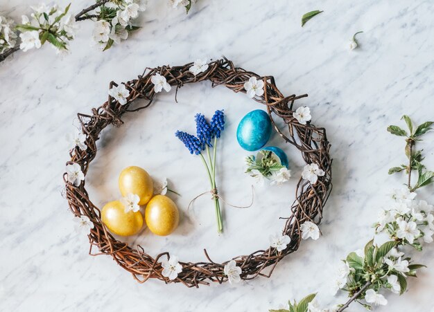 Corona de Pascua con huevos teñidos y flores de primavera y ramas de árboles florecientes laicos plana