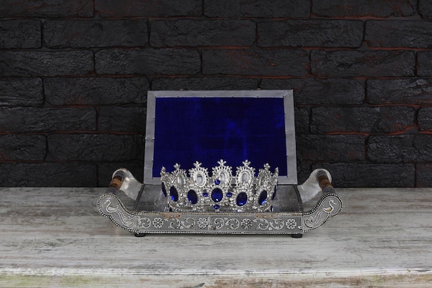Una corona plateada con una tapa azul descansa sobre una mesa frente a una pared de ladrillos.