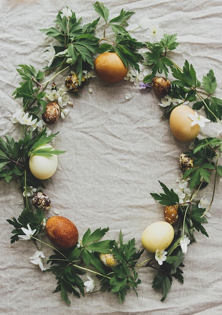 Corona rústica de Pascua hecha de huevos y pétalos de flores de primavera sobre lino rústico plano Estética