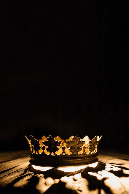 Foto una corona sobre un fondo negro está resaltada con un rayo dorado batalla por el trono