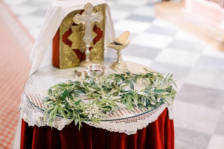 Foto coronas verdes estão na mesa ao lado de tigelas de prata, uma cruz e uma bíblia na igreja.