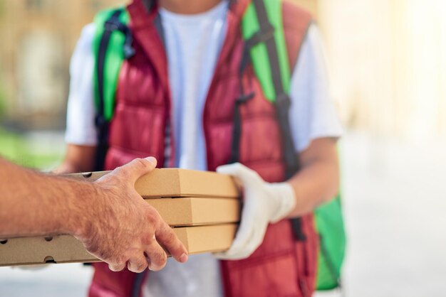 Coronavirus beschnittene Aufnahme eines männlichen Kuriers mit Schutzhandschuhen, der Kisten mit Pizza liefert