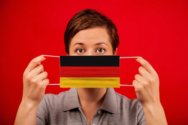 Coronavirus COVID-19 en Alemania. Mujer en máscara protectora médica con la imagen de la bandera de Alemania.