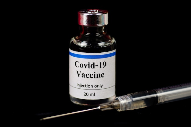 Coronavirus Covid 19 Impfstoffkonzept kleine Glasflasche mit silberner Kappe Nahaufnahme Detail auf Schwarz