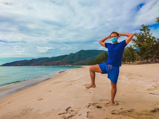 Coronavirus COVID 19 Jovem bonito praticando esportes realizando exercícios perto do mar pela manhã durante a quarentena Vida ativa na proteção cirúrgica de máscara facial de esterilização