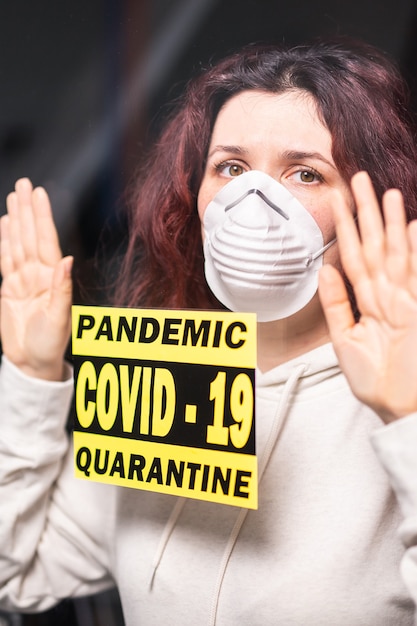 Foto coronavirus, cuarentena, covid-19 y concepto de pandemia. mujer triste y enferma de coronavirus mirando por la ventana