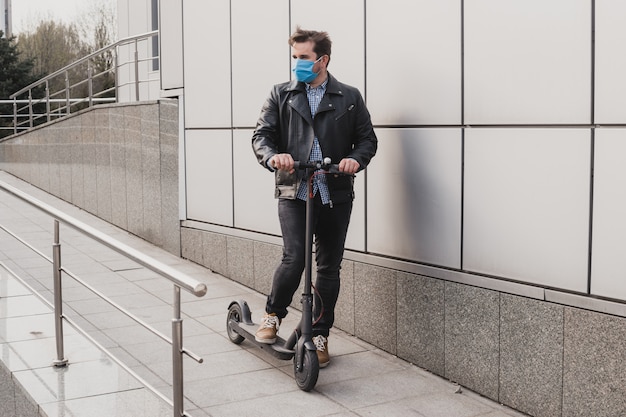 Coronavirus, enfermedad, infección, cuarentena, máscara médica, hombre con máscara en scooter eléctrico en segundo plano urbano