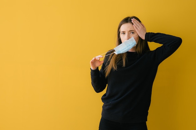 Coronavirus-Frau auf gelbem Hintergrund im Gesichtsschutz der chirurgischen Maske