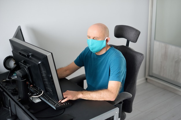 Coronavirus. Hombre trabajando desde casa con máscara protectora.