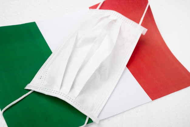 Coronavirus in Italien. Medizinische antibakterielle Maske auf dem Hintergrund der italienischen Flagge