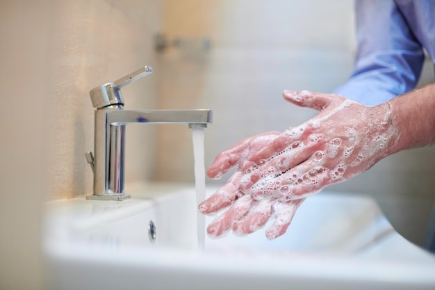 Coronavirus männliche wahende Hände im Badezimmer
