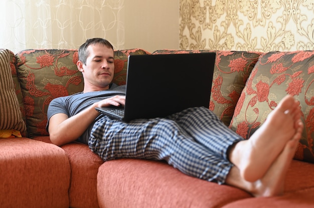 Coronavirus. Mann in Quarantäne für Coronavirus trägt Schutzmaske, er liegt auf der Couch.